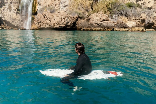 Uomo pieno del colpo che si siede sulla tavola da surf