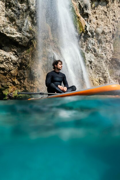 Uomo pieno del colpo che si siede sulla tavola da surf