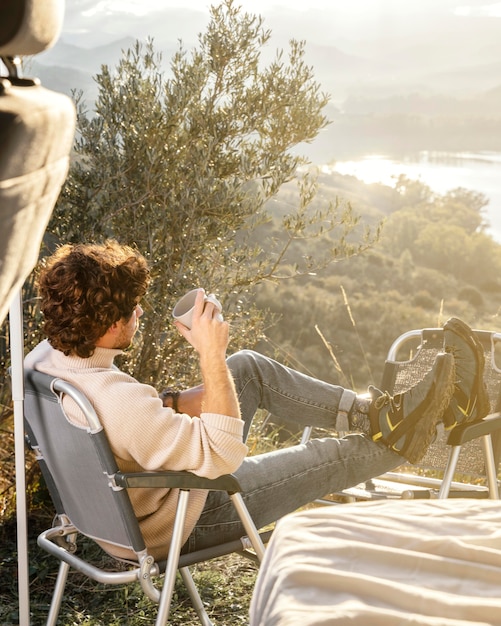 Uomo pieno del colpo che tiene tazza all'aperto