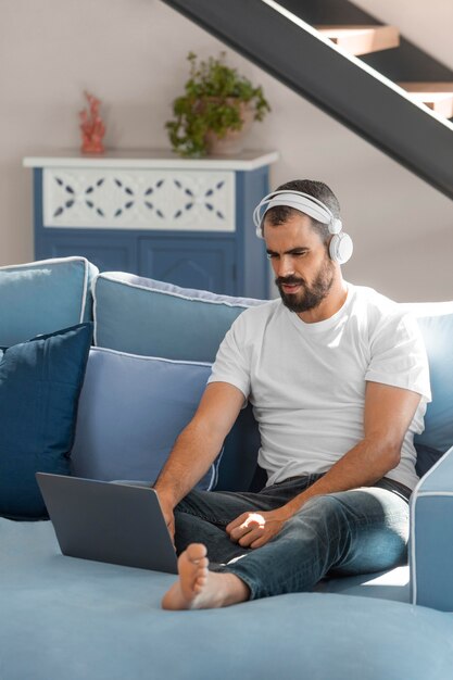 Uomo pieno del colpo con il computer portatile sul divano