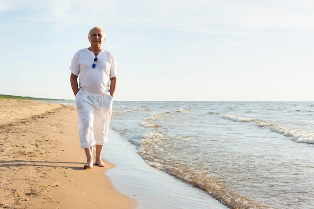 Uomo più anziano che cammina sulla spiaggia godendo della vista