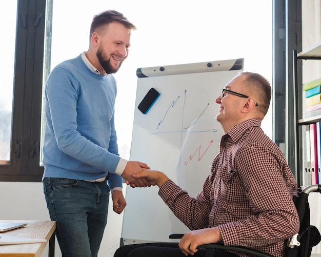 Uomo positivo che si congratula uomo disabile per il suo impegno