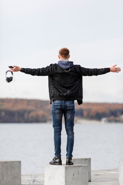 Uomo posteriore di vista che tiene le sue cuffie mentre godendo della vista