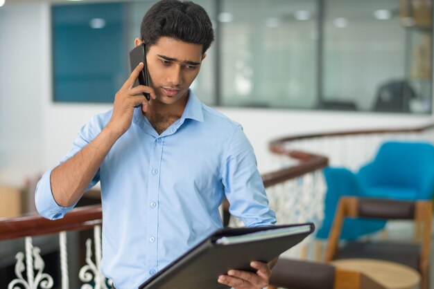 Uomo premuroso che discute i dati mentre parlando sul telefono cellulare