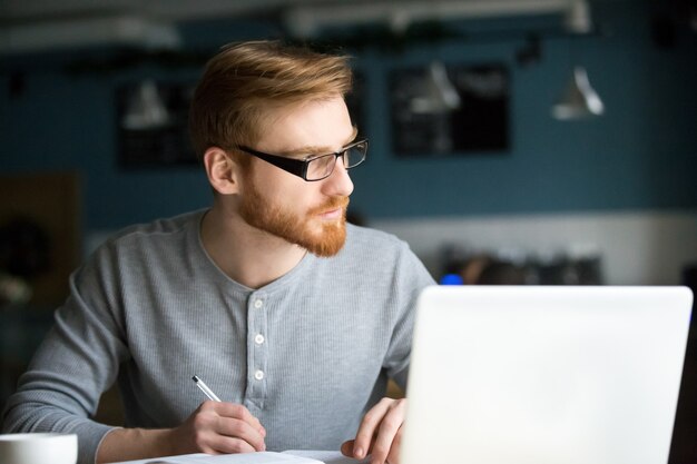 Uomo premuroso che pensa alle nuove note di scrittura di idea in caffè