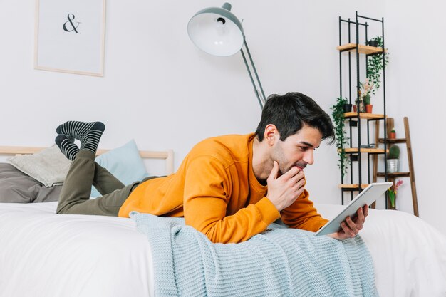 Uomo premuroso che utilizza compressa sul letto