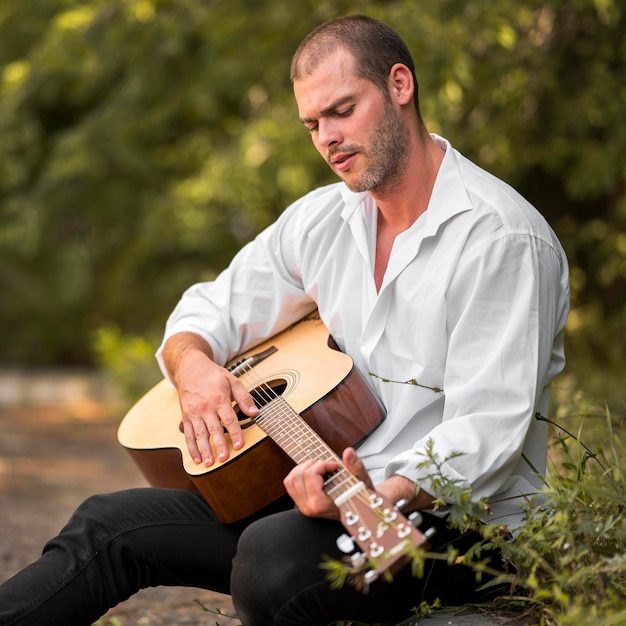 Uomo seduto a suonare la chitarra nella natura