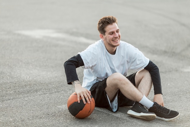 Uomo seduto con un pallone da basket