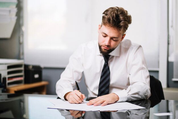 Uomo seduto e scrivendo in ufficio