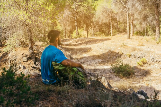 Uomo seduto in foresta