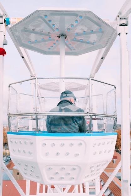 Uomo seduto in una ruota panoramica Ferris carosello cabina durante un giro