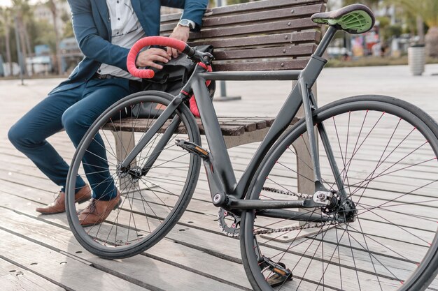 Uomo seduto su una panchina accanto alla sua bici all'aperto