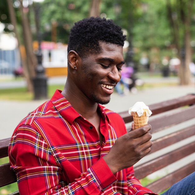 Uomo seduto su una panchina e mangiare il gelato