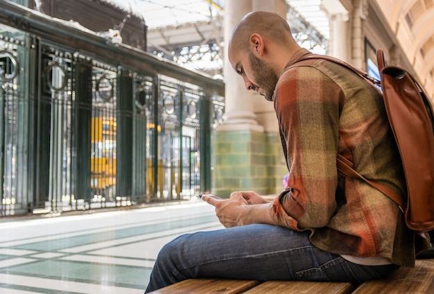 Uomo seduto su una panchina e usando il cellulare