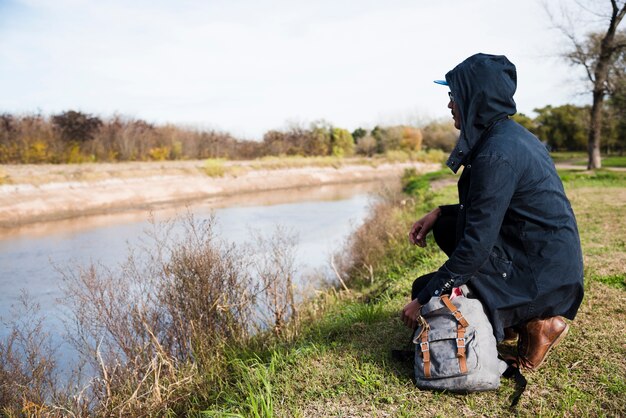 Uomo seduto sulla riva del fiume