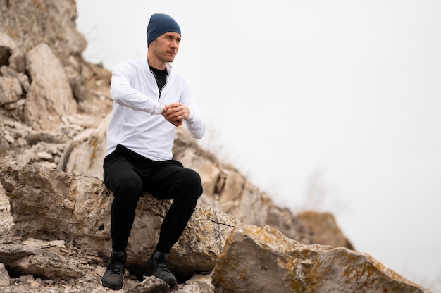 Uomo seduto sulle rocce in natura