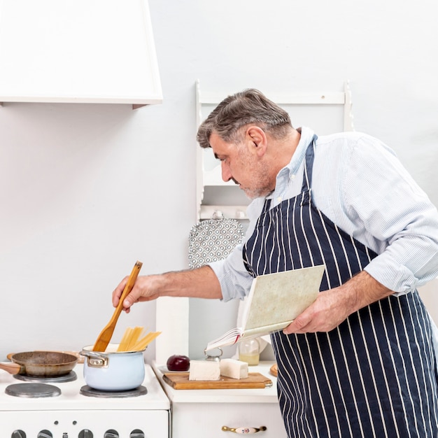 Uomo senior che cucina con il cucchiaio di legno