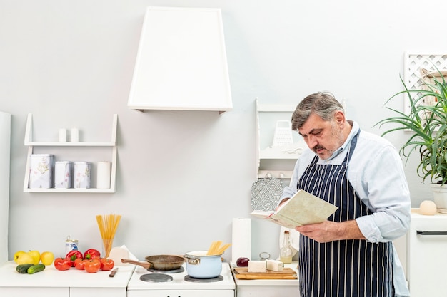 Uomo senior che guarda in un libro di cucina