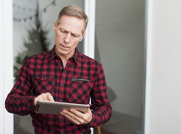 Uomo senior concentrato che osserva sulla sua compressa