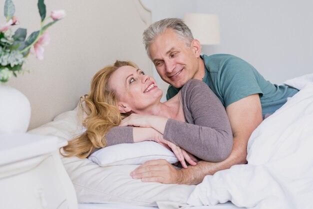 Uomo senior e donna adorabili insieme a letto