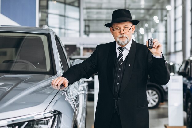 Uomo senior in una sala d'esposizione dell'automobile che sceglie un'automobile