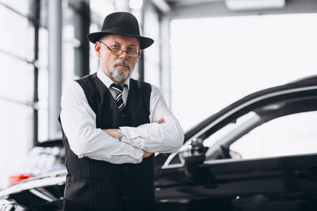 Uomo senior in una sala d'esposizione dell'automobile che sceglie un'automobile