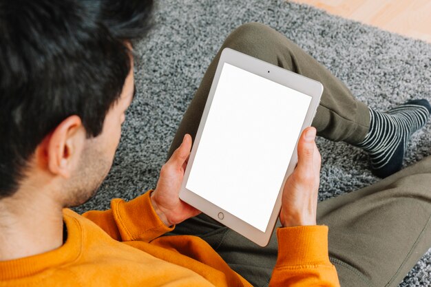 Uomo senza volto con tablet sul pavimento