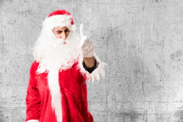 Uomo serio con costume di Babbo Natale che mostra il dito indice