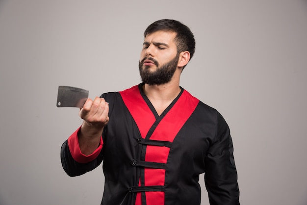 Uomo serio con la barba che tiene un coltello affilato.