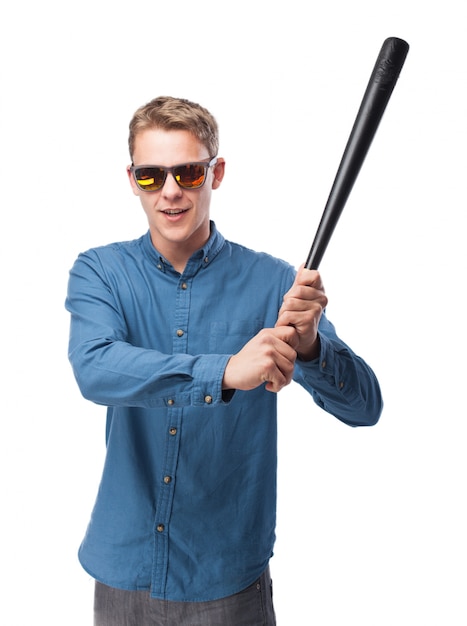 Uomo serio con una mazza da baseball e occhiali da sole