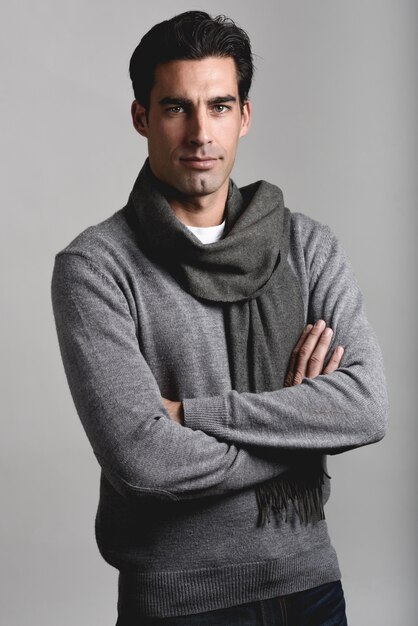 Uomo serio con uno sfondo grigio e una sciarpa