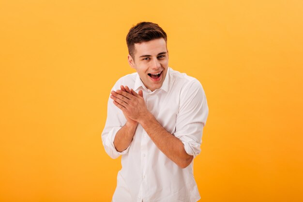 Uomo sleale felice in camicia bianca che si tiene per mano insieme e che esamina la macchina fotografica