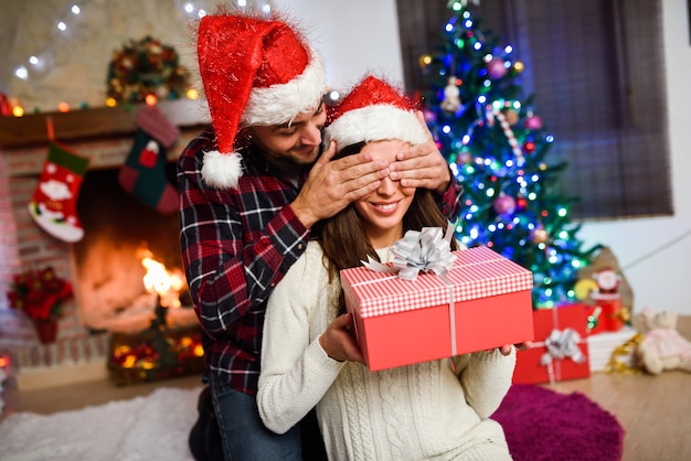 Uomo sorprendente la sua ragazza con un regalo di Natale