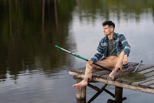 Uomo sorridente a tutto campo che pesca