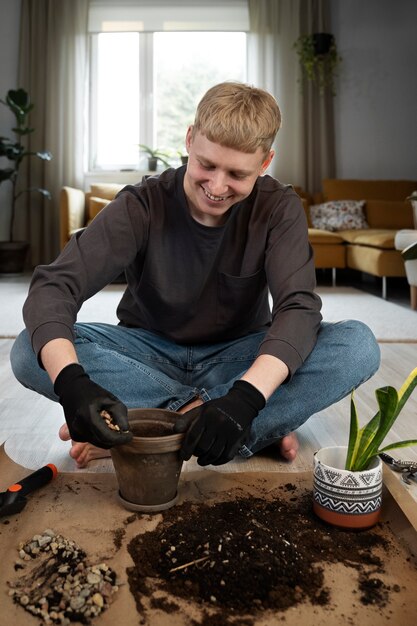 Uomo sorridente a tutto campo che trapianta le piante