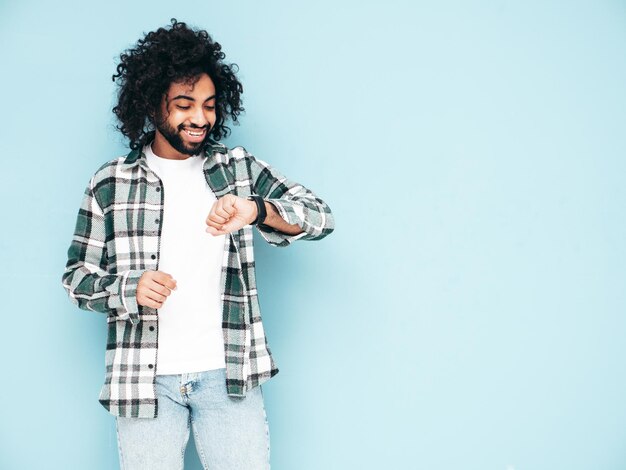 Uomo sorridente bello dei pantaloni a vita bassa che posa nello studio