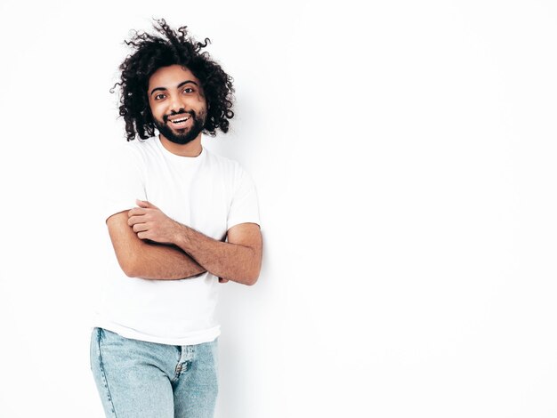 Uomo sorridente bello dei pantaloni a vita bassa che posa nello studio