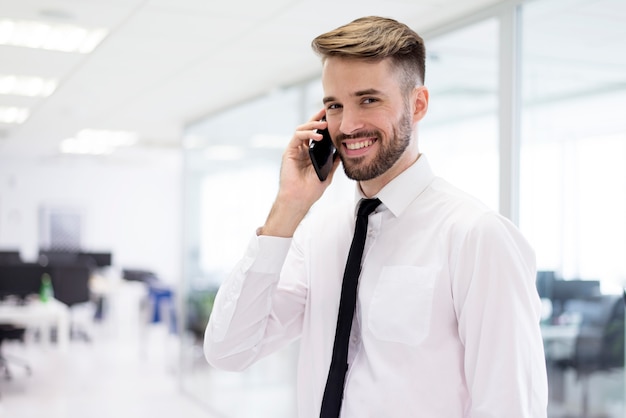 Uomo sorridente che comunica sul suo cellulare