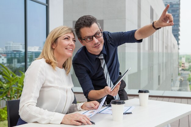 Uomo sorridente che indica e che mostra collega femminile qualcosa all&#39;aperto.