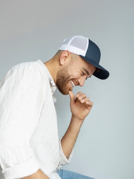 Uomo sorridente che posa con la vista laterale del cappello del camionista