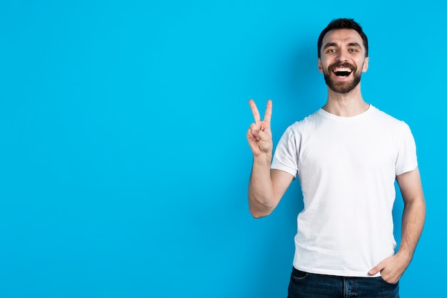 Uomo sorridente che posa mentre facendo il segno di pace