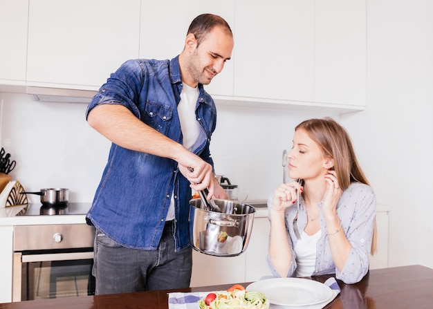 Uomo sorridente che serve cibo a sua moglie in cucina