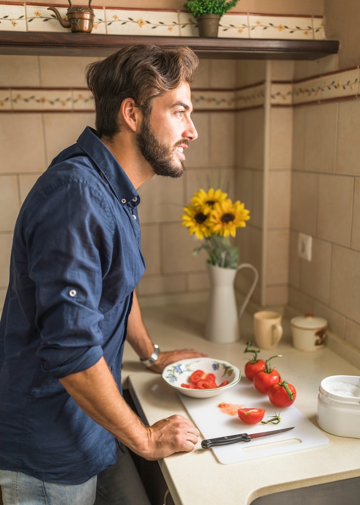 Foto gratuito uomo sorridente che sta al contatore di cucina che osserva via