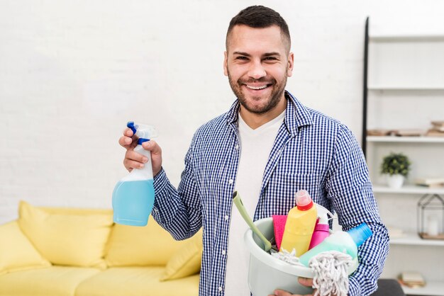 Uomo sorridente che tiene secchio con prodotti per la pulizia