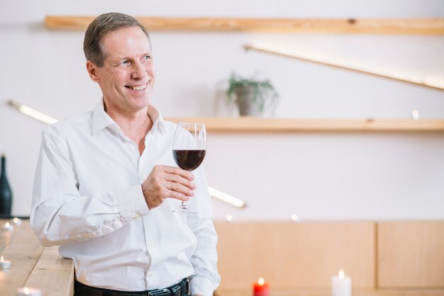 Uomo sorridente che tiene un bicchiere di vino