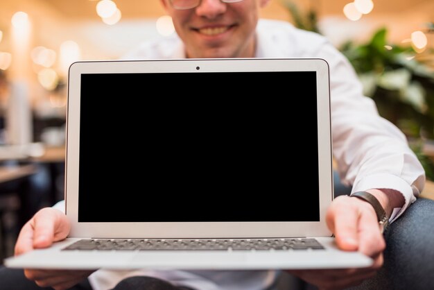 Uomo sorridente che tiene un computer portatile aperto con schermo nero