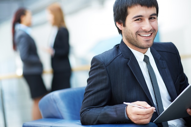 Uomo sorridente che tiene una penna e una cartella