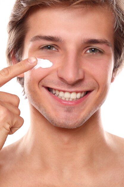 uomo sorridente che usando la crema per il viso