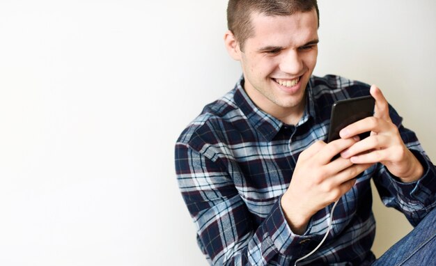 Uomo sorridente che utilizza uno smartphone a casa