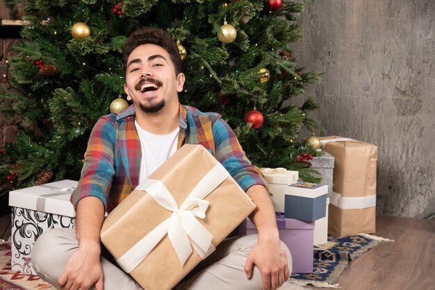 Uomo sorridente che vuole conoscere l'interno della confezione regalo.